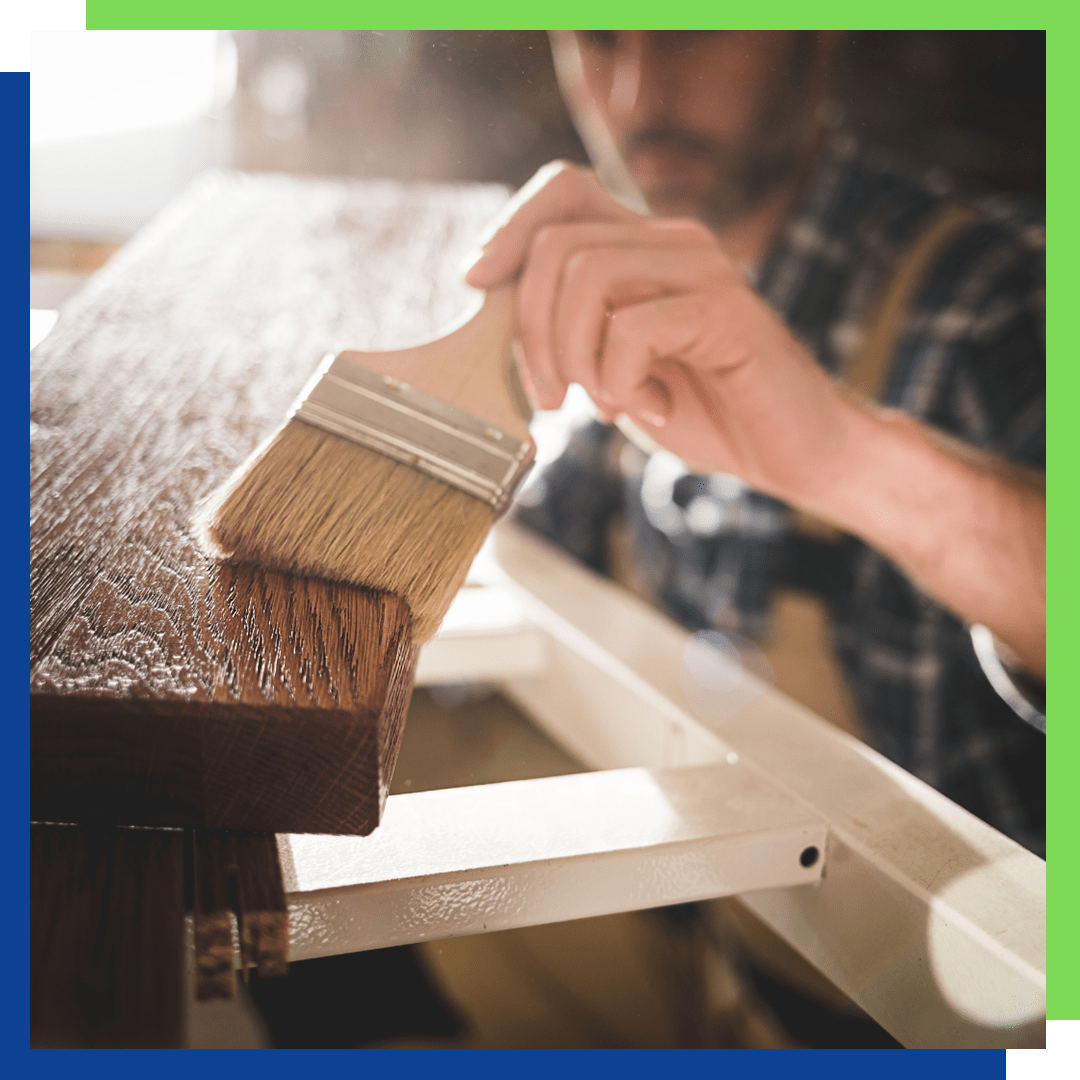 A furniture repairman staining furniture